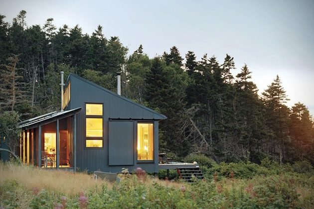 Grey corrugated cabin glowing at dusk in a meadow