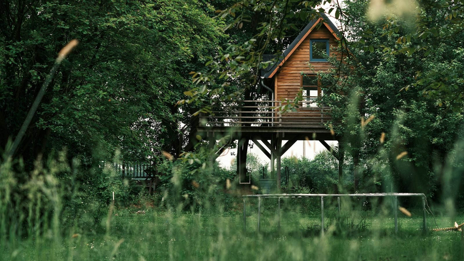 Wooden treehouse on stilts in green meadow