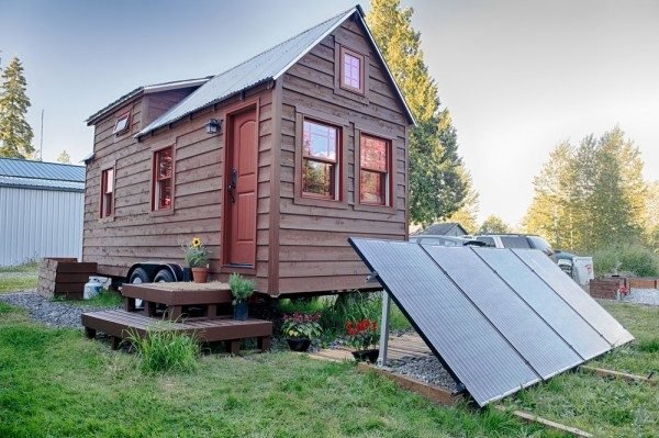 Tumbleweed-style tiny house on wheels in orchard