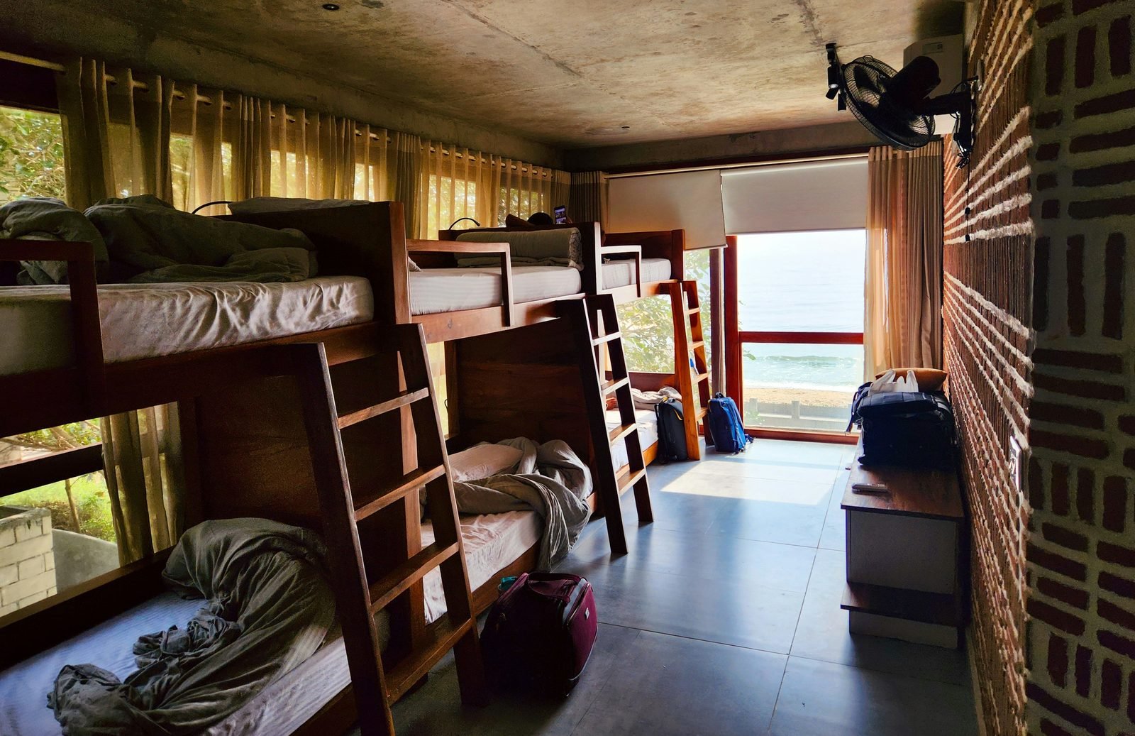 Bunk beds with sea view through open window — the volunteer and guest dormitory