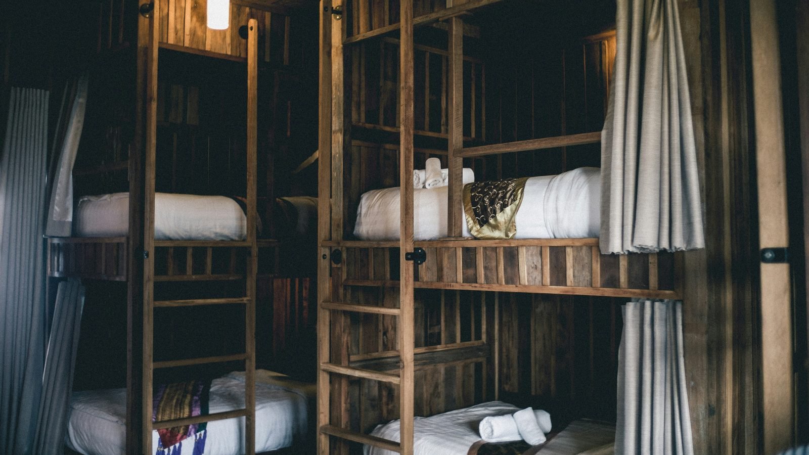 Warm timber bunk beds with curtains — the guest dormitory
