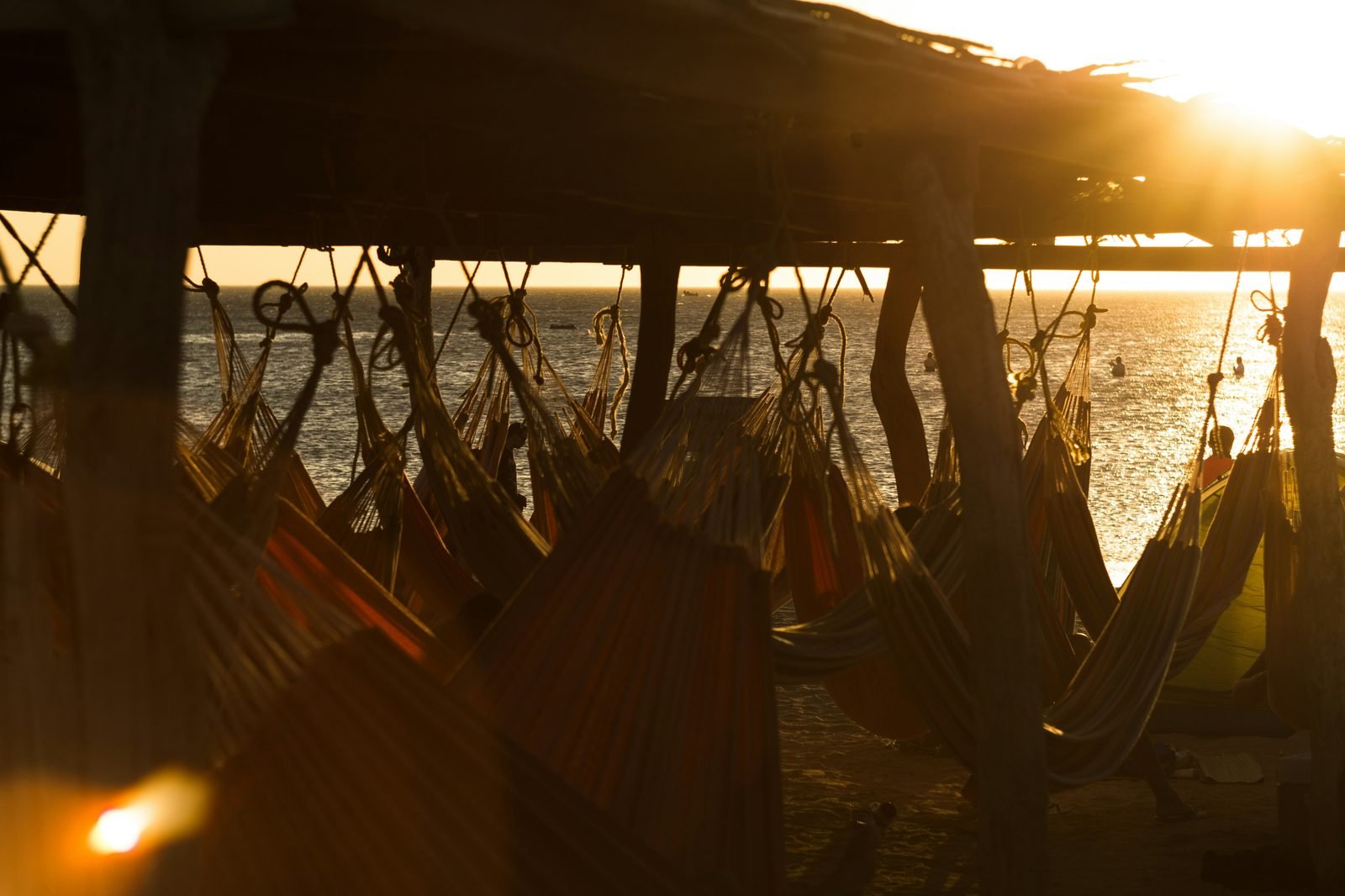Rows of hammocks at sunset over the sea — a place of rest and arrival