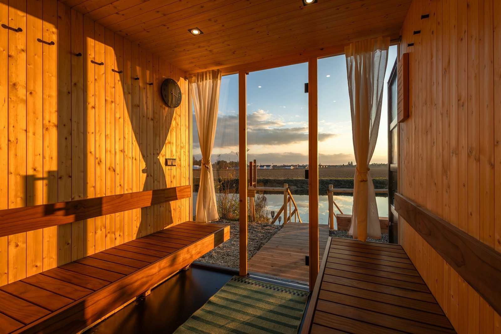Sauna interior with sunset view over pond — wood-fired, beside cold plunge