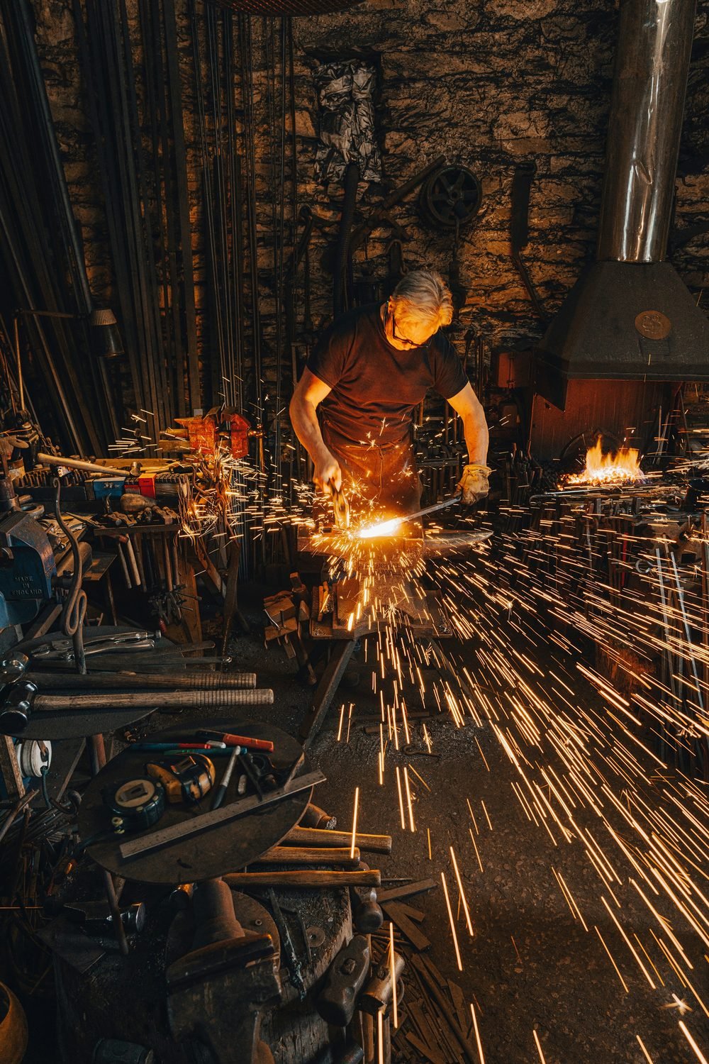 Blacksmith at stone forge, sparks and firelight